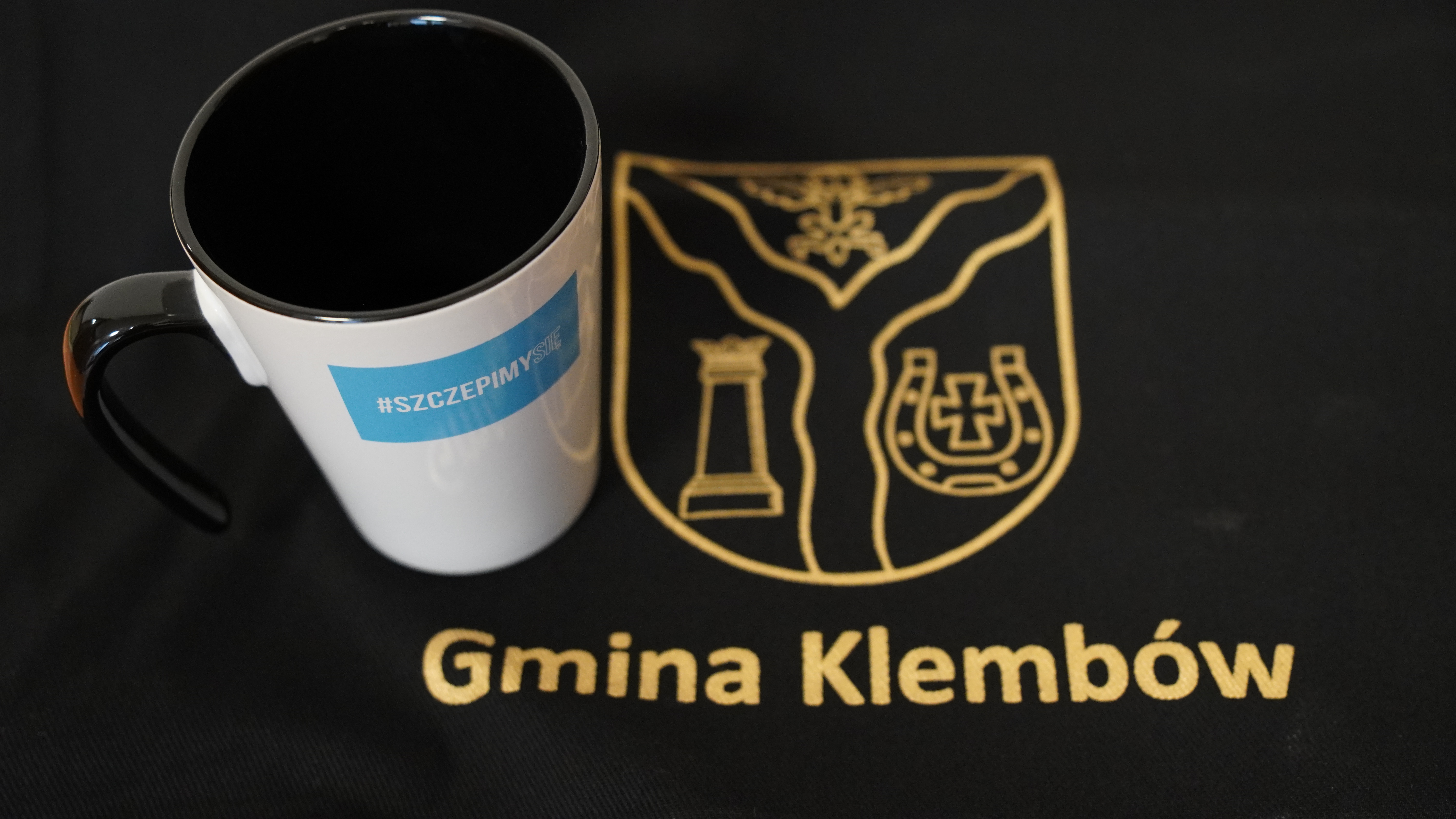 Kubek Gminy Klembów z hasłem Szczepimy Się na tle torby z herbem i napisem Gmina Klembów;